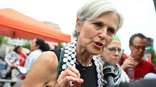 Jill Stein wears a keffiyeh and speaks into a reporter’s mic