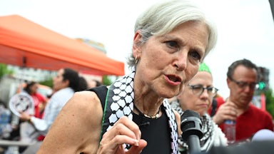 Jill Stein wears a keffiyeh and speaks into a reporter’s mic