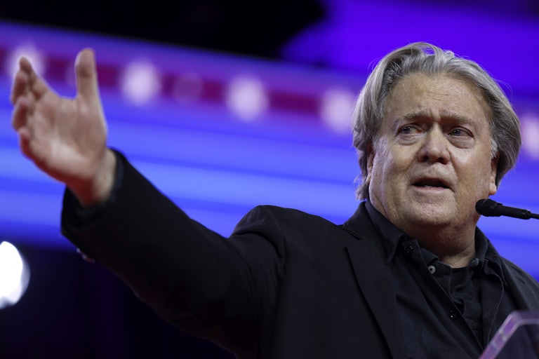 Steve Bannon speaking at a mic and stretching his right arm outward