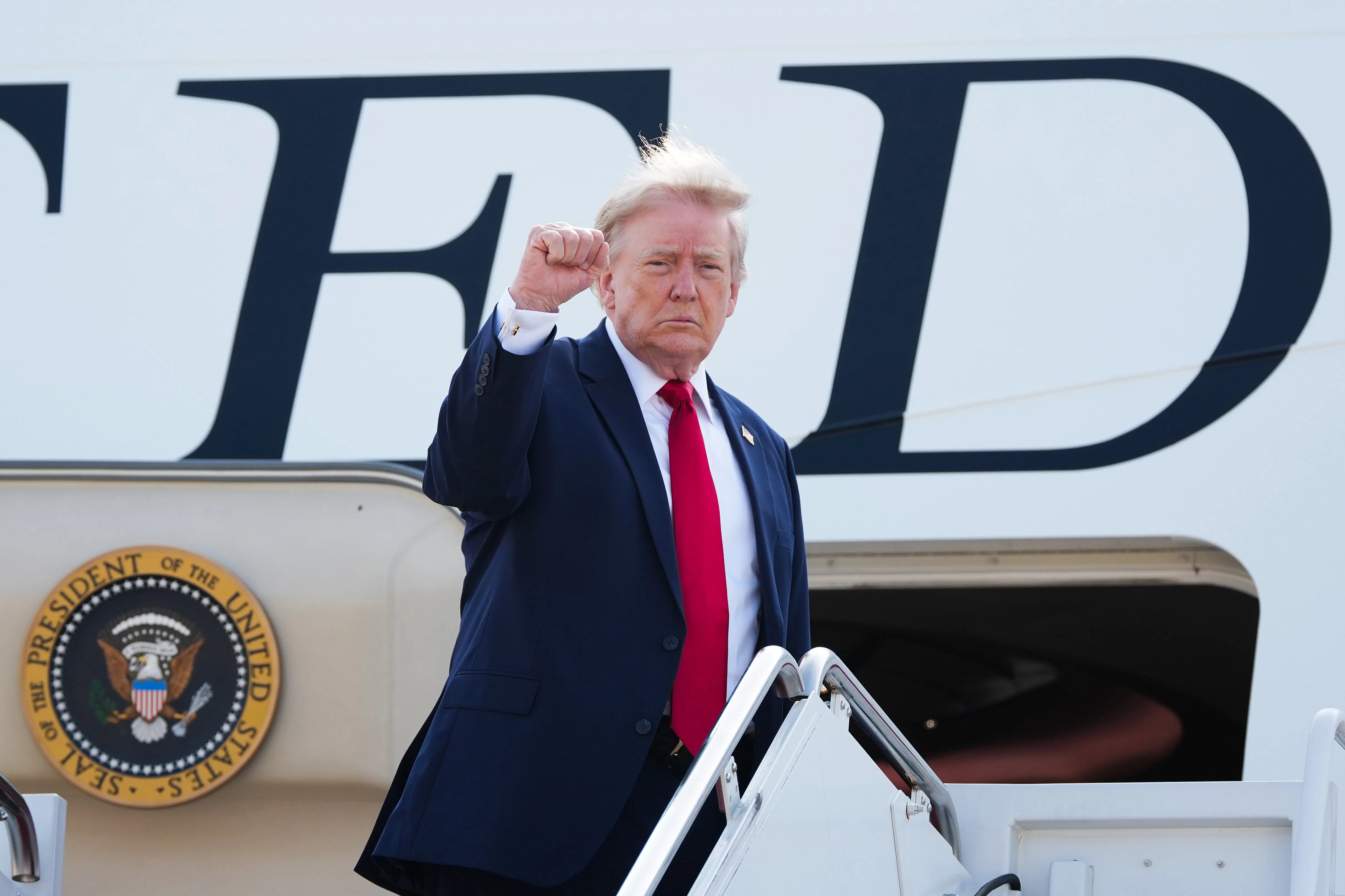Donald Trump raises his fist while boarding Air Force One