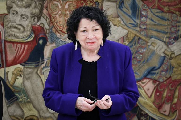 Supreme Court Justice Sonia Sotomayor holds her glasses while standing in the royal palace in Madrid, Spain