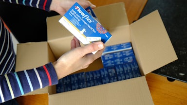 A woman unboxes a box of COVID-19 rapid antigen tests.
