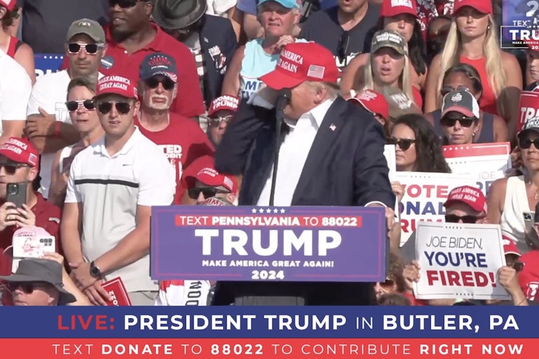 Trump holding his right ear on campaign rally stage