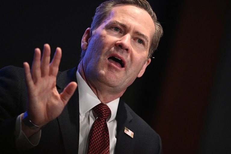 National Security Adviser Mike Waltz holds up a hand while speaking