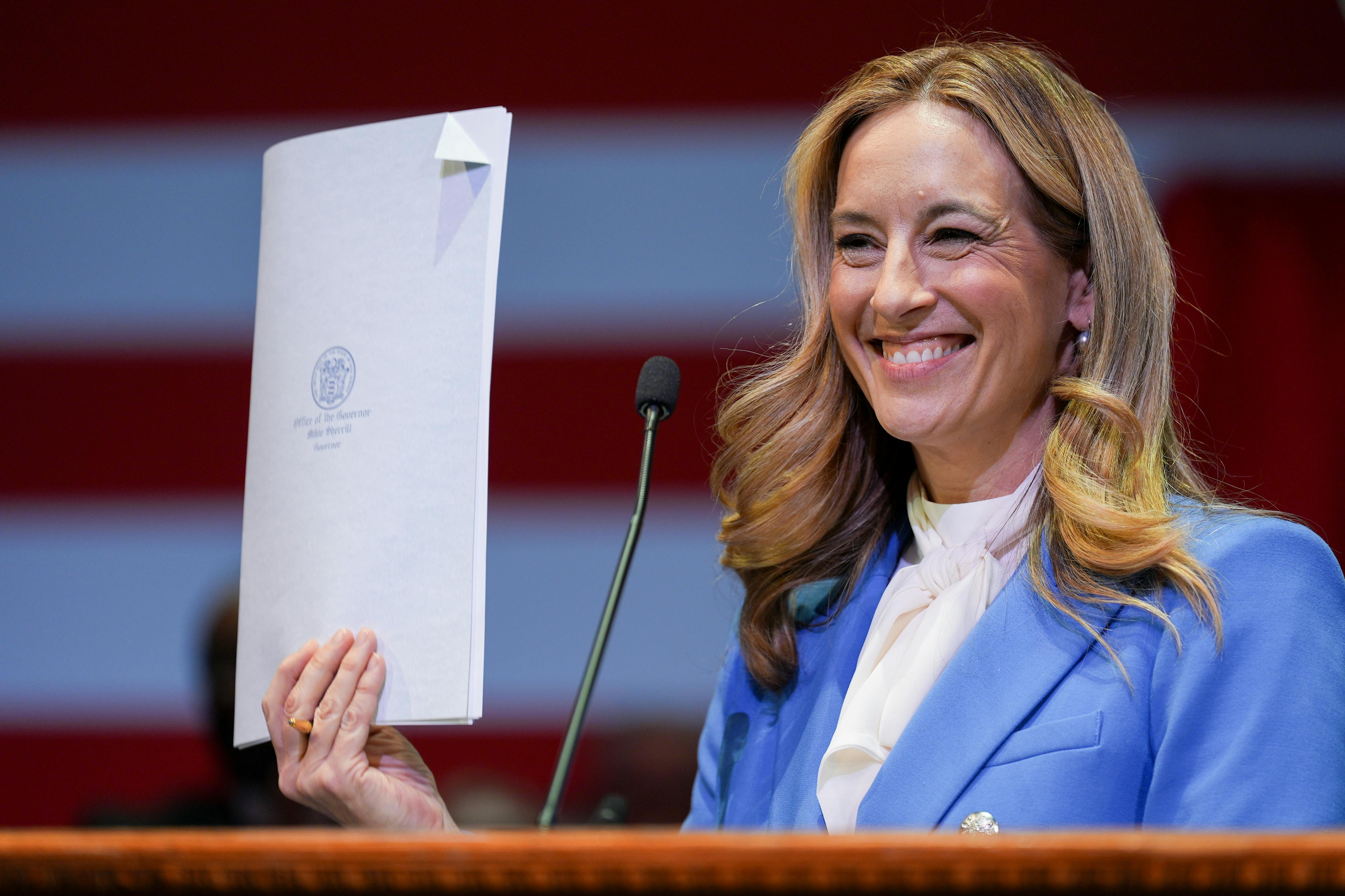 New Jersey Governor Mikie Sherrill smiles and holds up a signed bill.