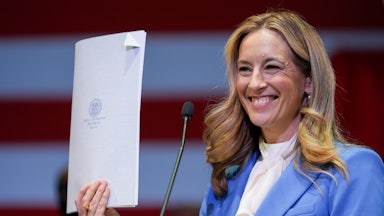 New Jersey Governor Mikie Sherrill smiles and holds up a signed bill.