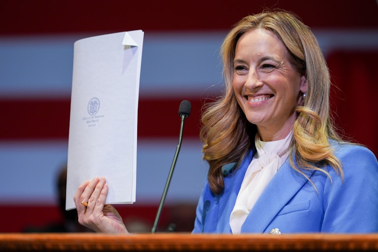 New Jersey Governor Mikie Sherrill smiles and holds up a signed bill.