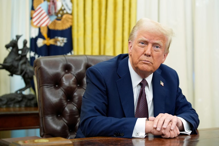 Donald Trump rests his hands on his desk in the Oval Office