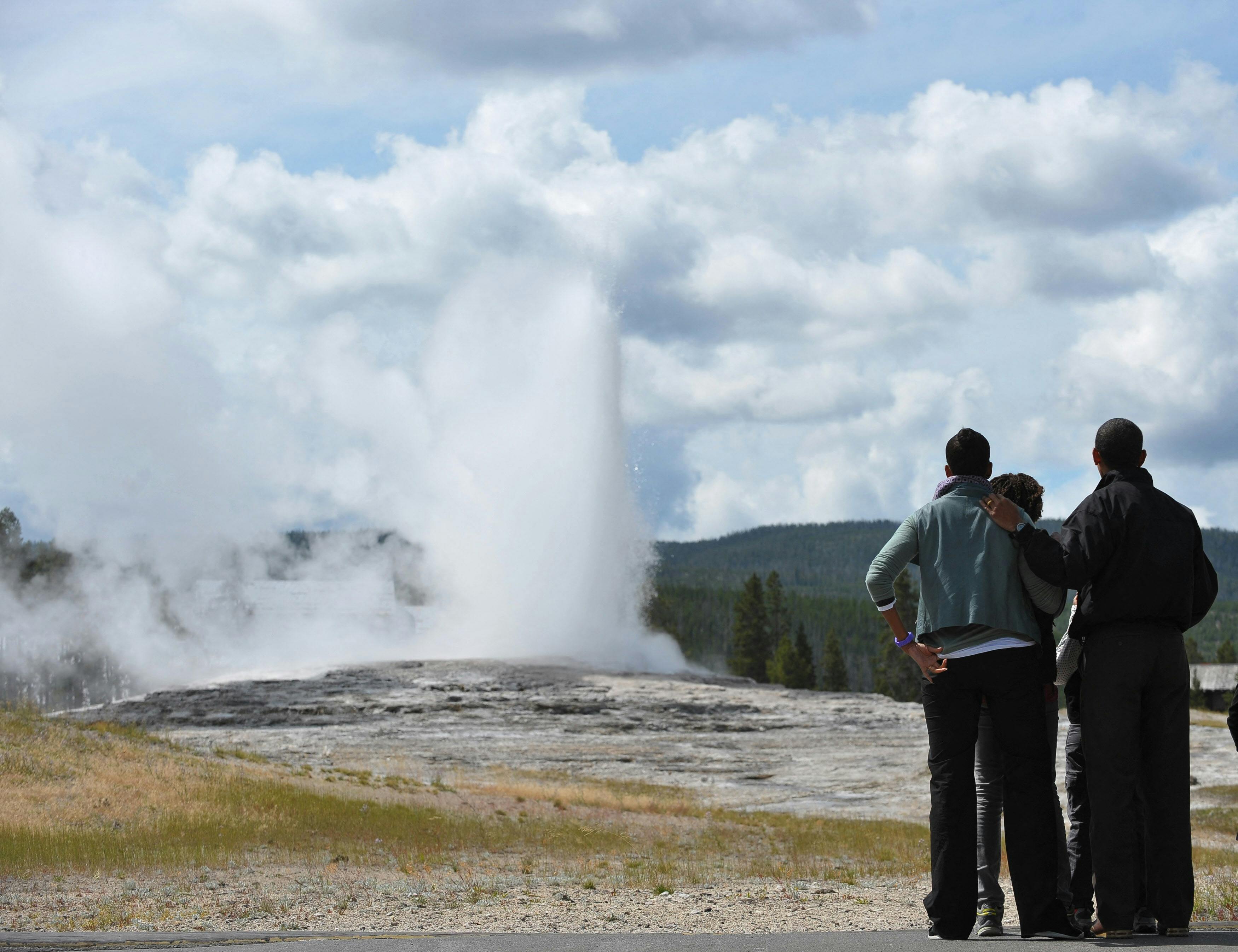 Three black people at a national mark. A woman puts her arm around a man.