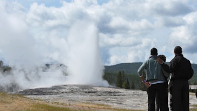 Three black people at a national mark. A woman puts her arm around a man.