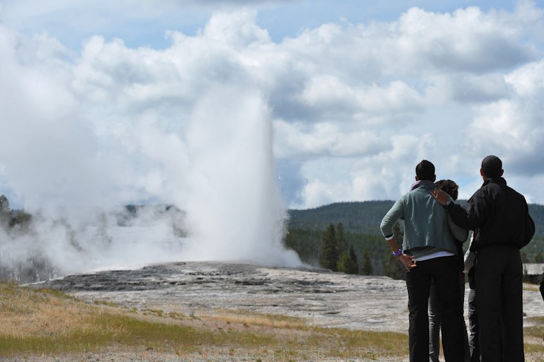 Three black people at a national mark. A woman puts her arm around a man.