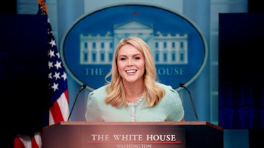 Karoline Levitt smiles while standing at the White House press room podium.