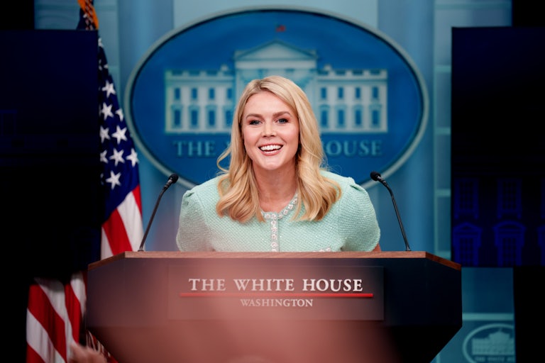 Karoline Levitt smiles while standing at the White House press room podium.
