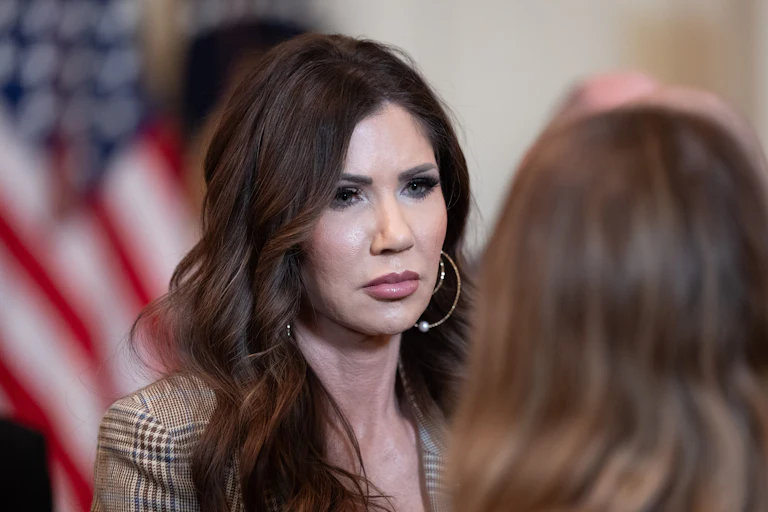 Homeland Security Secretary Kristi Noem stands during an event