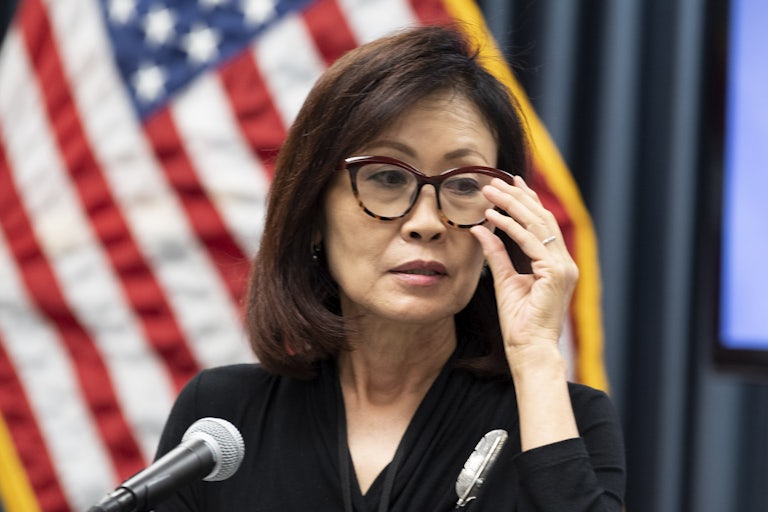 Michelle Steel adjusts her glasses. A U.S. flag is behind her.