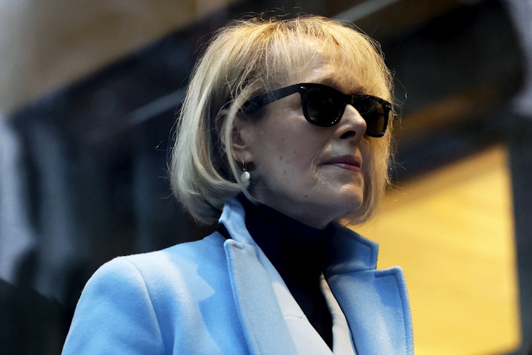 E. Jean Carroll outside wearing a blue coat and sunglasses. This is a profile shot.