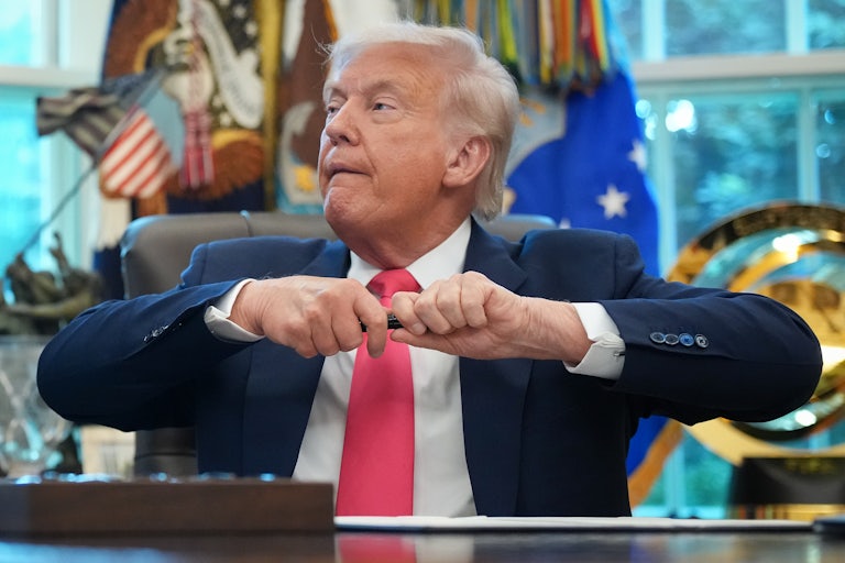 Donald Trump uncaps a pen while sitting at his desk in the Oval Office
