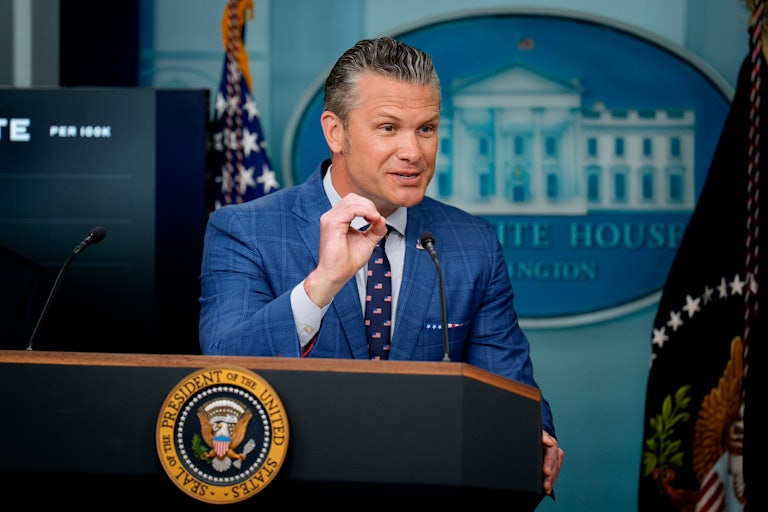 Defense Secretary Pete Hegseth gestures while speaking at the podium in the White House briefing room