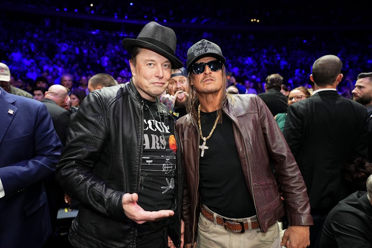 Elon Musk, wearing a fedora and an "Occupy Mars" t-shirt and otherwise looking like a character in a Tim Robinson sketch, stands next to Kid Rock.
