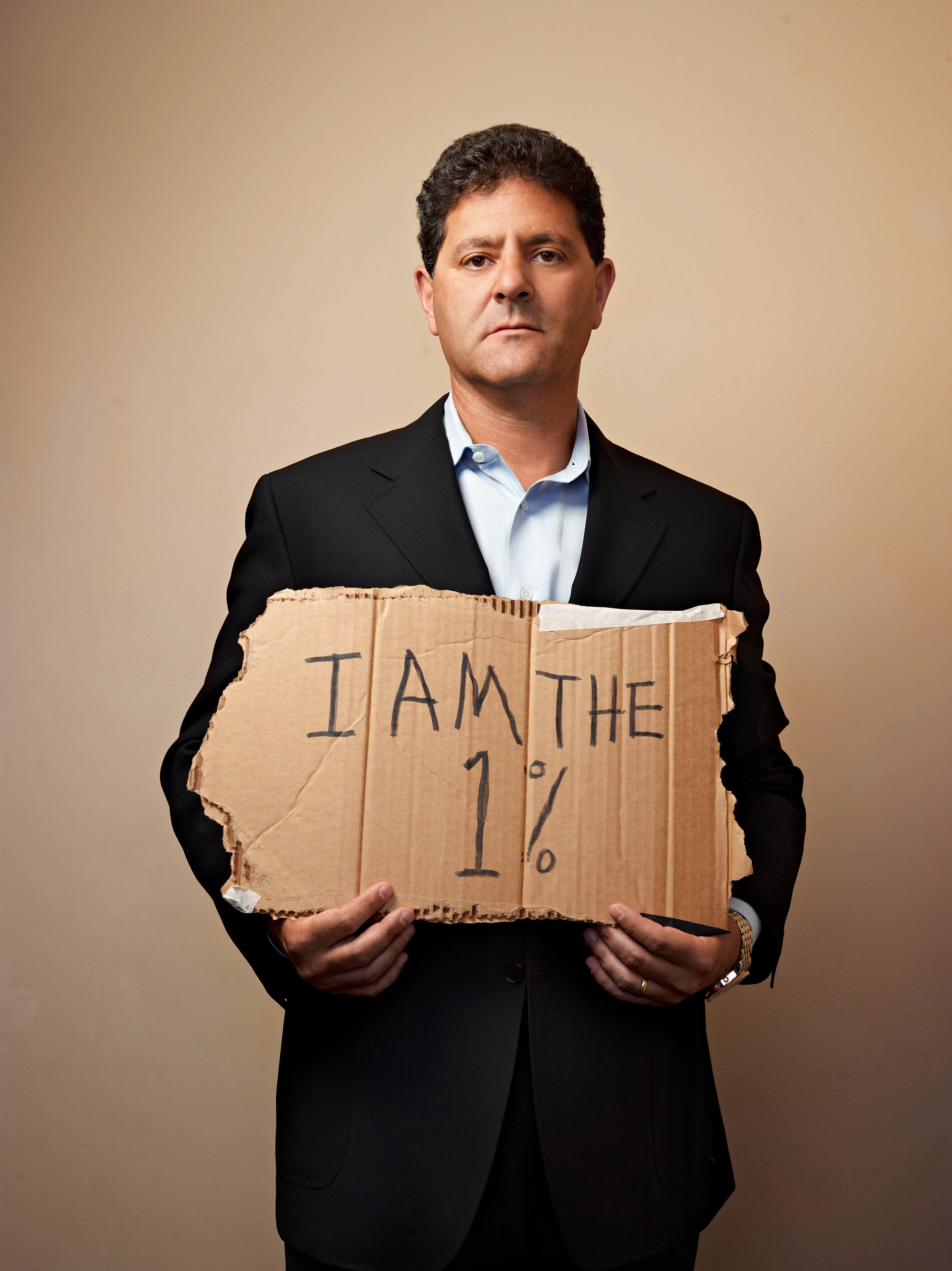 Entrepreneur Nick Hanauer holding a torn piece of cardboard that reads 'I am the 1 percent' in black market 