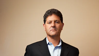 Entrepreneur Nick Hanauer holding a torn piece of cardboard that reads 'I am the 1 percent' in black market