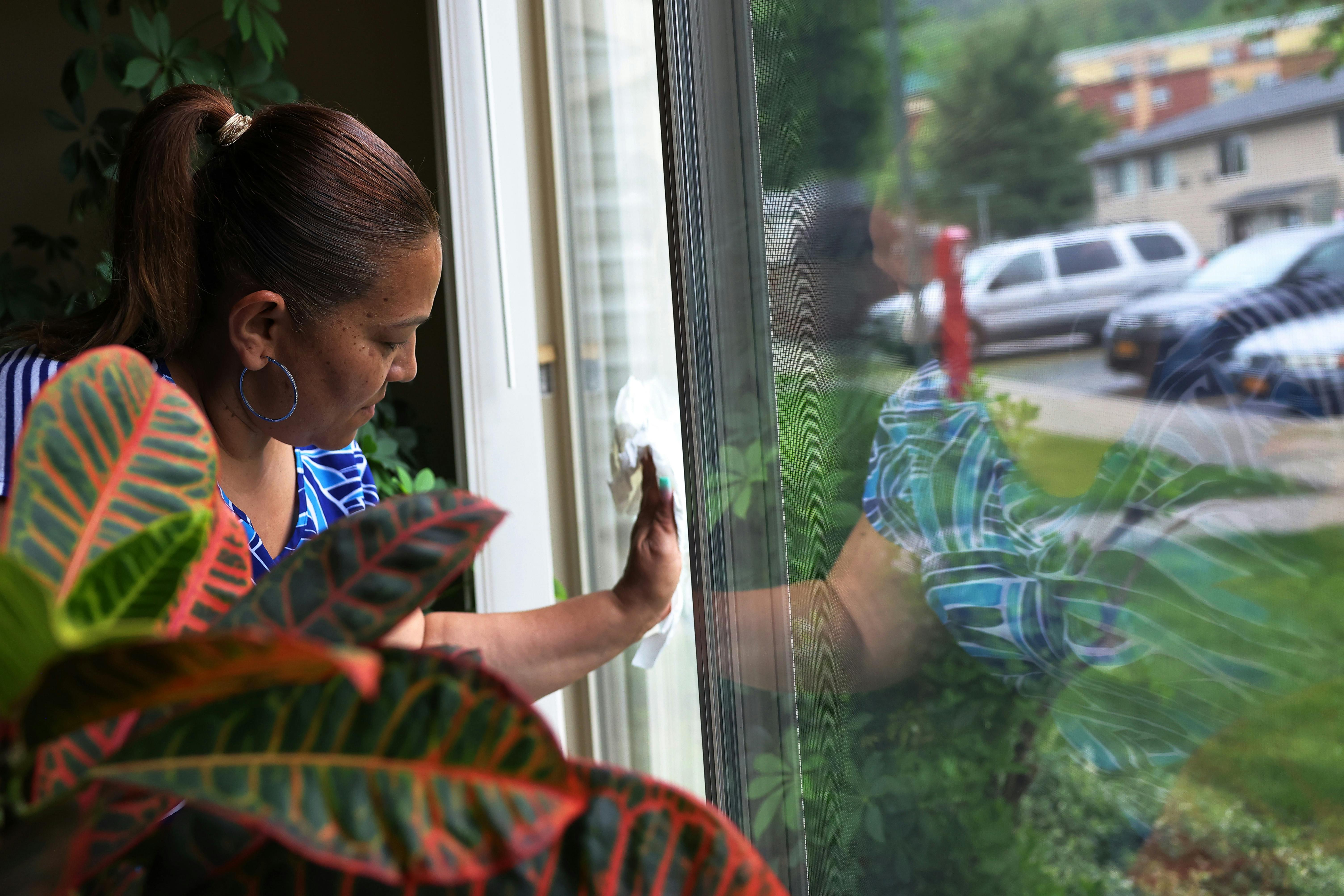 Home health aide cleans window