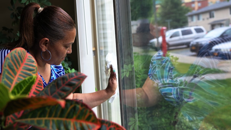 Home health aide cleans window