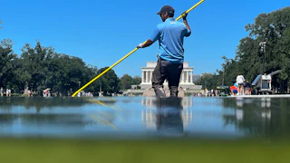 A worker cleans algae out of the Reflecting Pool