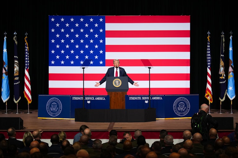 Donald Trump raises his arms to the side while speaking to military leaders at Quantico