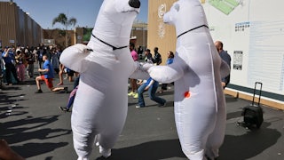 Two people in polar bear suits hold hands while dancing.