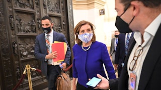 House Speaker Nancy Pelosi walks through the U.S. Capitol, thronged by aides and reporters.