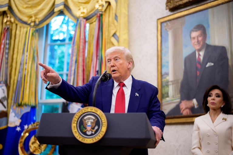 Donald Trump points while standing at the presidential poidum in the White House. Jeanine Pirro stands in the background.