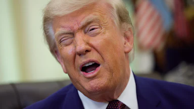Donald Trump makes a winking face while speaking in the Oval Office
