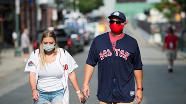 Fans wear masks on Landsdowne Street as they walk to Fenway Park in Boston.