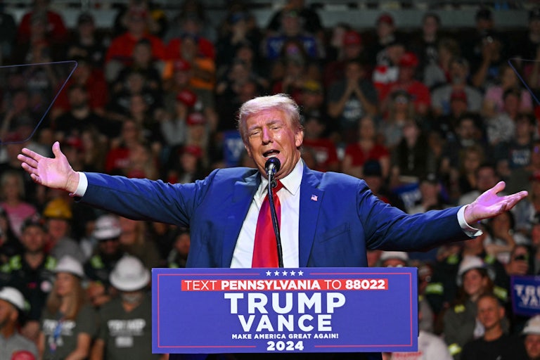 Donald Trump holds his arms out while speaking at a campaign event