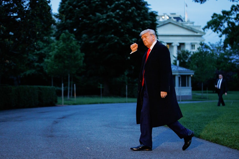 Donald Trump walks outside the White House and raises a fist in the air as if in victory.