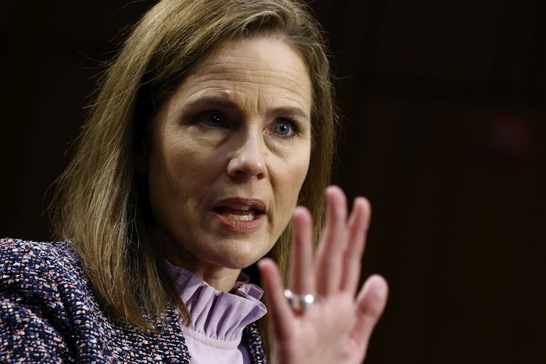 Supreme Court Justice Amy Coney Barrett speaks and holds her hand up as if telling someone to stop.