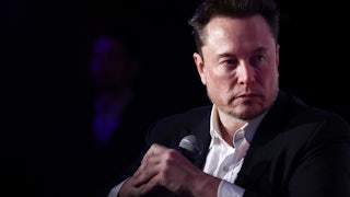 Elon Musks holds a microphone while seated.