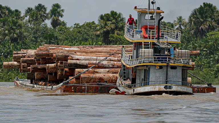 A vessel transports logs on a raft.