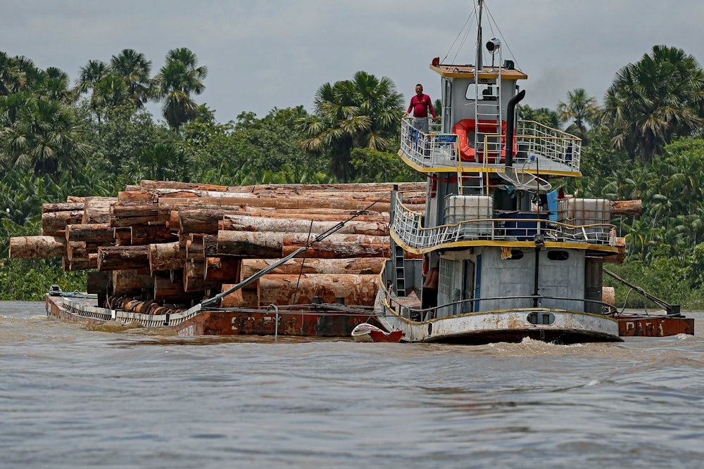 A vessel transports logs on a raft.