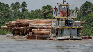 A vessel transports logs on a raft.