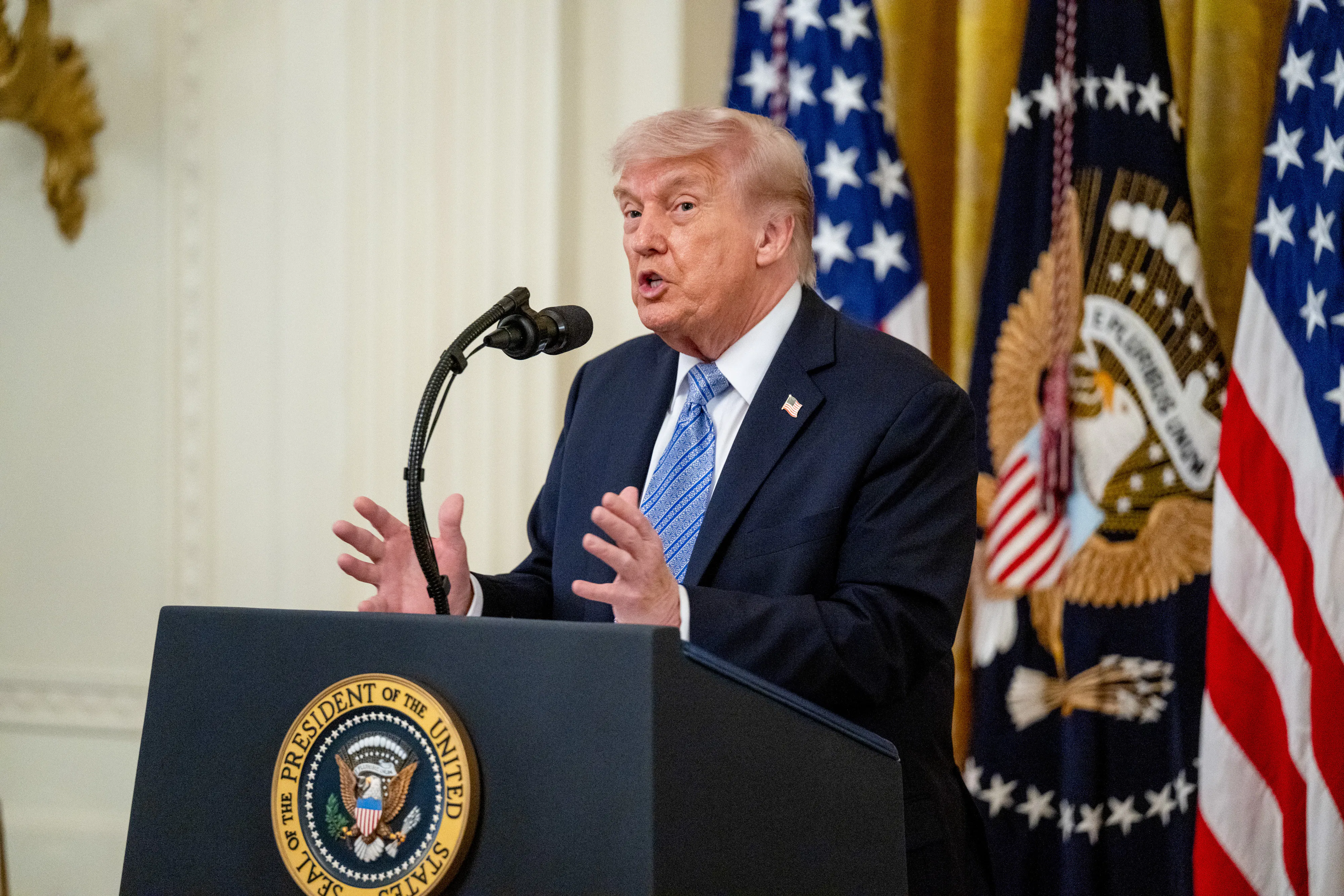 Donald Trump gestures and speaks at a podium