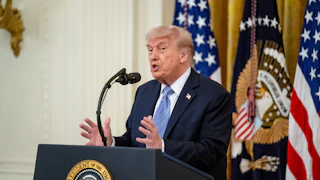 Donald Trump gestures and speaks at a podium