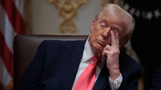 Donald Trump touches his eye with two fingers while sitting in his Cabinet meeting