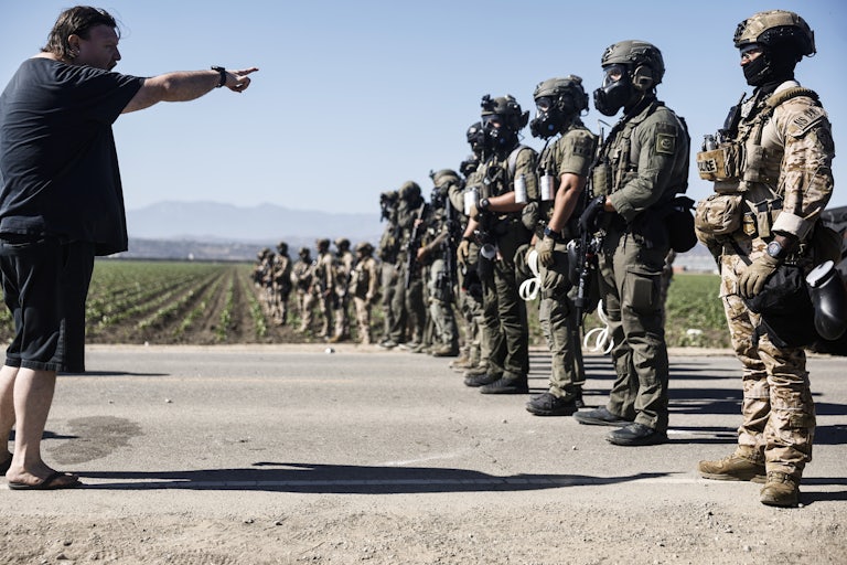 A man points his finger and shouts at heavily armed federal agents who are blocking a group of protesters from interfering with an immigration raid.