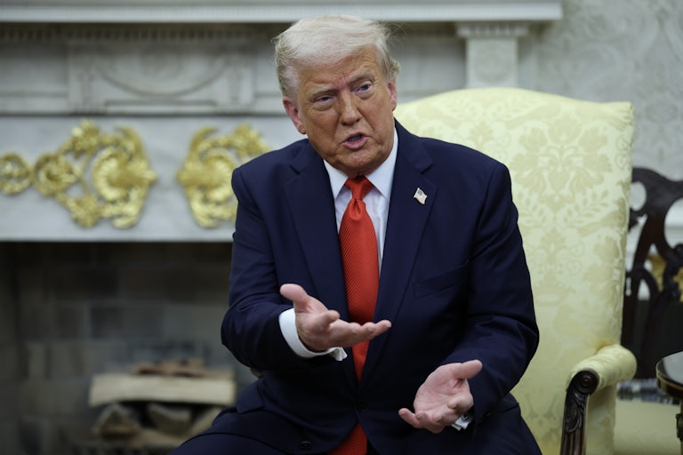 Donald Trump speaks and makes a hand gesture while talking to someone not pictured. He sits in the Oval Office of the White House.