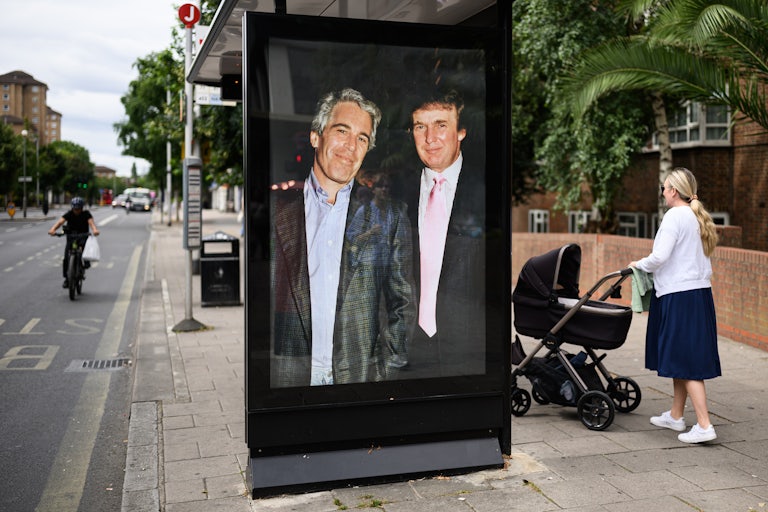 A photograph of Donald Trump and convicted child sex offender Jeffrey Epstein is displayed in a bus shelter in London. Others walk around.
