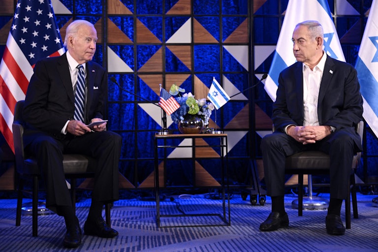 Joe Biden and Benjamin Netanyahu sit on two chairs near each other.
