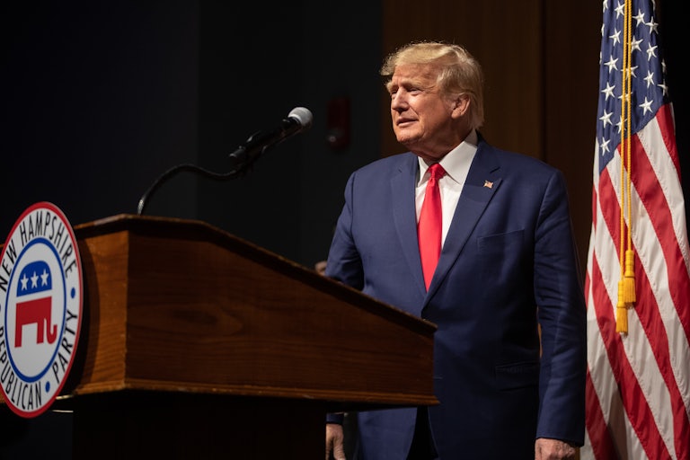 Donald Trump makes a weird face on stage. A podium in front of him has a sign that reads "New Hampshire Republican Party."