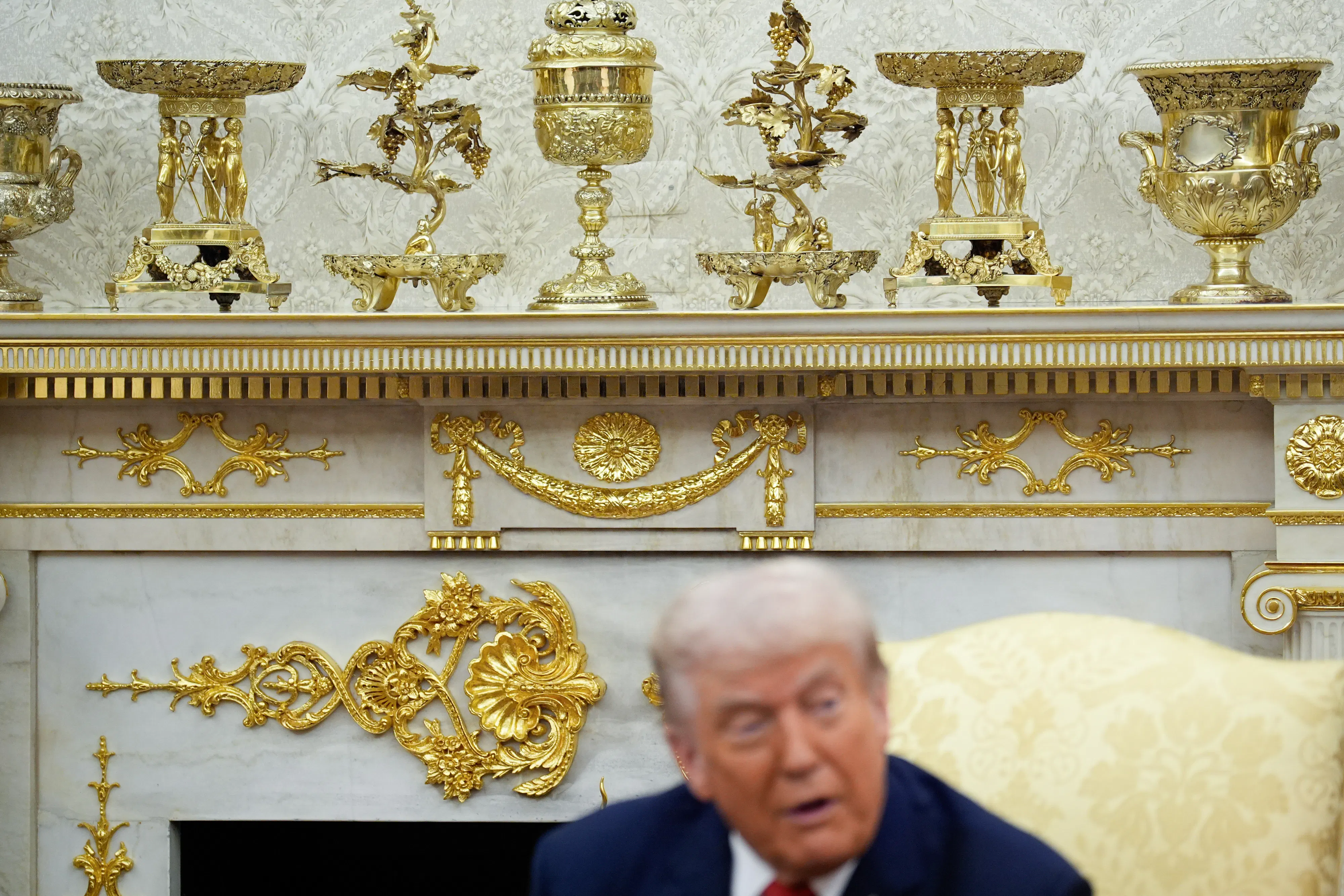 Trump sits in front of gold decor in oval office
